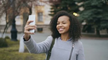 Neşeli karışık yarış öğrenci kız Üniversitesi yakınındaki smartphone ile görüntülü görüşme, söz