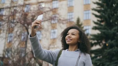 Neşeli Afro-Amerikan öğrenci kız Üniversitesi yakınındaki smartphone ile görüntülü görüşme, söz