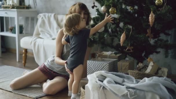 Szczęśliwą matką i jej małą córeczkę, grając w pobliżu choinki w domu — Wideo stockowe
