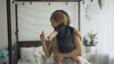 Mutlu genç anne ve küçük şirin kız yatak odası evde yatakta yakınındaki dans