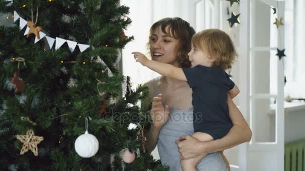 Happy mother and her little daughter playing near the Christmas tree at home — Stock Video