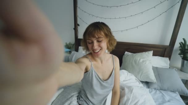 POV de mujer alegre que tiene chat de vídeo en línea con amigos usando la cámara del teléfono inteligente mientras está sentado en la cama en casa — Vídeos de Stock