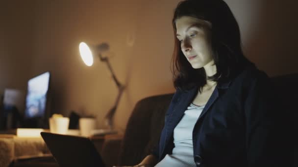 Junge fröhliche Frau arbeitet nachts im Büro mit Laptop und tippt Nachricht — Stockvideo