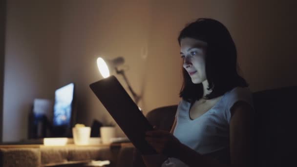 Молода приваблива жінка використовує планшетний комп'ютер для онлайн-покупки вдома вночі — стокове відео