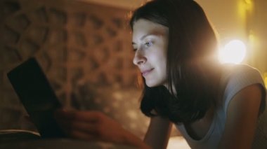 Evde yatakta yatan gece zaman tablet bilgisayar kullanan genç güzel kadın Close-Up
