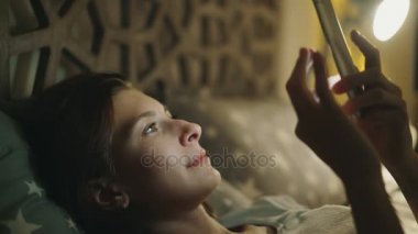 Geceleri evde yatakta yatan smartphone kullanan genç gülümseyen kadın Close-Up
