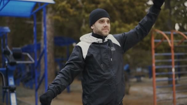 Joven atleta hombre calentando antes de entrenar en el parque de invierno — Vídeo de stock