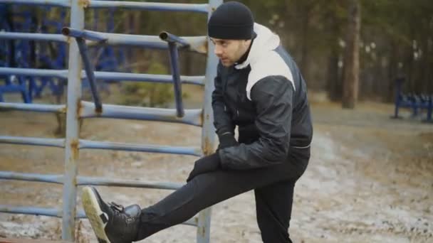 Jonge atleet man warming-up vóór de training opleiding in winter park — Stockvideo