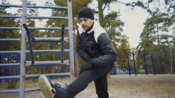 Attraktiver Mann Läufer macht Stretching-Übung Vorbereitung für das morgendliche Training und Joggen im Winterpark — Stockvideo