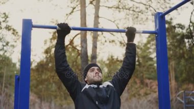Kış park açık havada pull-up egzersiz yapan genç atletik erkek
