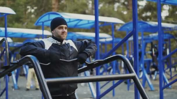 Muscular young man doing exercise in outdoor gym in winter park — Stock Video