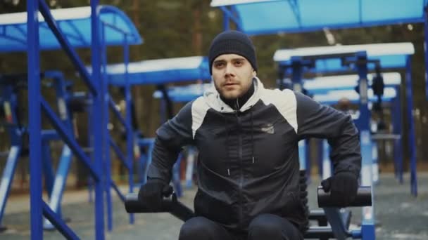 Musculoso joven haciendo ejercicio en el gimnasio al aire libre en el parque de invierno — Vídeo de stock