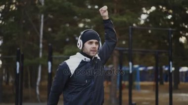 Yakışıklı adam kış Park müzik dinleme sırasında germe egzersiz yaparak kulaklık