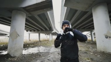 Boksör adam boks egzersiz sırasında dinlemek müzik kentsel konumda açık havada kışın yaparak Kulaklığımda görüntüsünü izleme