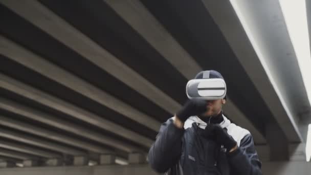 Boxeador joven en VR 360 golpes de entrenamiento de auriculares en la lucha de realidad virtual en la ubicación urbana al aire libre en invierno — Vídeo de stock