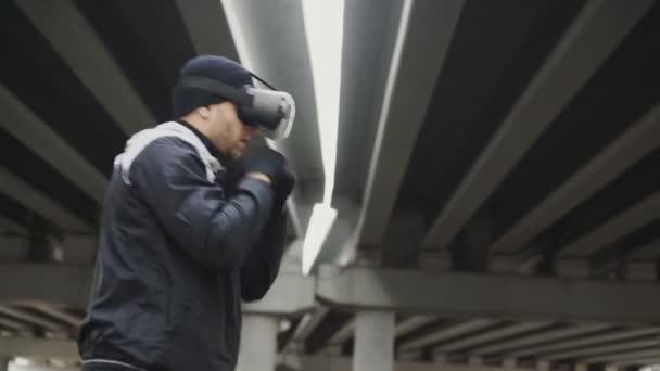 Vr 360 ヘッドセット トレーニング格闘技ボクシング男が冬に屋外都市の場所に仮想現実の戦いでパンチします。 — ストック動画