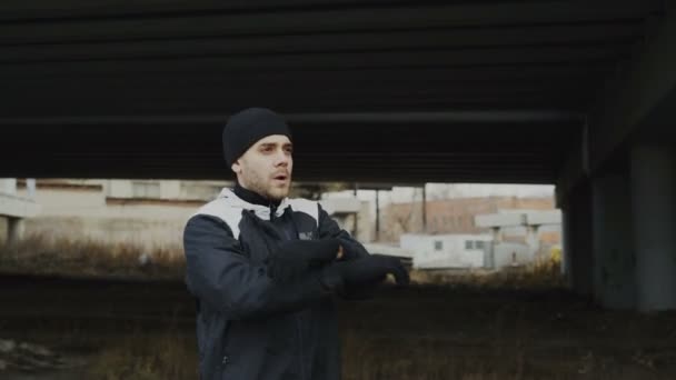 Atleta atractivo hombre calentando antes de entrenar en la ubicación urbana al aire libre en la temporada de invierno — Vídeos de Stock