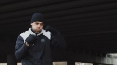 Konsantre adam boksör boks egzersiz kentsel konumda açık havada kışın yaparak Slowmotion