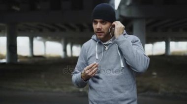 Sportif yakışıklı runner üzerine koyarak kulaklık ve kışın açık havada şehir konumda çalışan başlatır