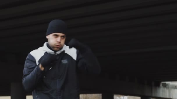 Lento movimento de homem concentrado boxeador fazendo exercício de boxe em localização urbana ao ar livre no inverno — Vídeo de Stock