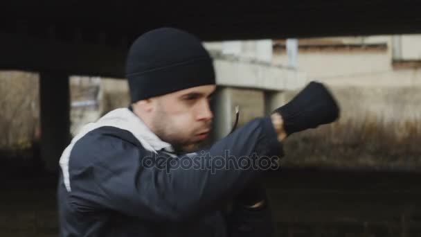 Lento movimento de homem esportivo boxeador fazendo exercício de boxe em localização urbana ao ar livre no inverno — Vídeo de Stock