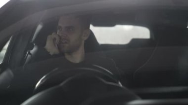 Açık havada araba içinde otururken telefonu konuşurken sinirli öfkeli işadamı