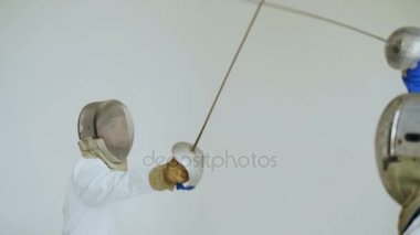 İki eskrimcilerin eskrim beyaz arka plan üzerinde saldırı ve savunma alýþtýrmalarda eğitim sahip