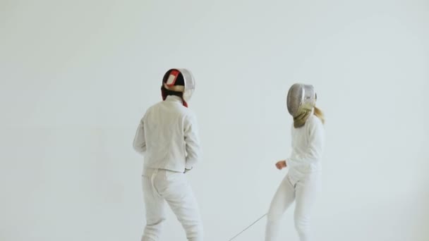 Молодая фехтовальщица, занимающаяся фехтованием с тренером в белой студии в помещении — стоковое видео