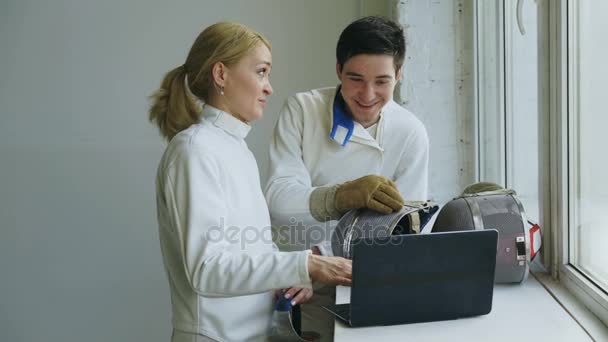 Twee jonge schermers man en vrouw kijken schermen competitie op laptopcomputer en ervaringen voor de opleiding binnen — Stockvideo