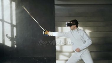 Konsantre fencer adam pratik VR kulaklık kullanarak ve simülatör rekabet oyun kapalı eğitim egzersizleri eskrim