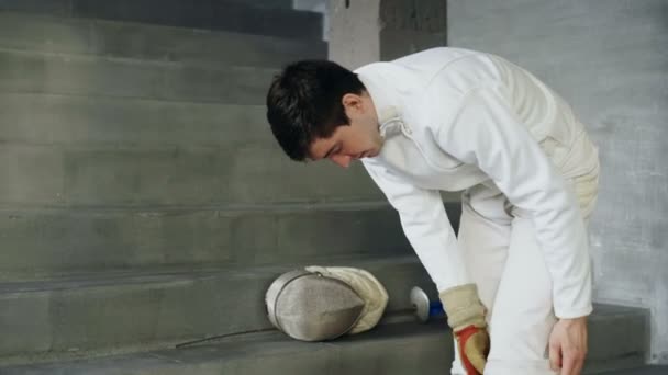 Fencer adam koruyucu giysi ve kask üzerinde koyarak hazırlamak rekabet kapalı eskrim için — Stok video