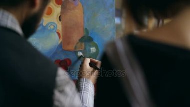 Öğretim ve genç kız boyama temelleri Sanat Atölyesi gösterilen yetenekli sanatçı adam arkadan görünüm