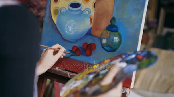 Vista posterior de cerca de la mujer artista con pintura de pincel bodegón cuadro sobre lienzo en el estudio de arte — Vídeos de Stock