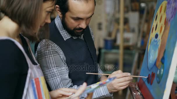 Profesora de arte calificada que muestra y discute los conceptos básicos de la pintura al estudiante en clase de arte — Vídeos de Stock