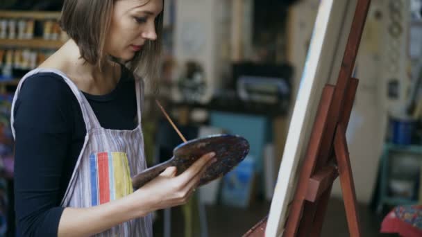 Junges Malermädchen in Schürze malt Stillleben-Bild auf Leinwand im Kunstunterricht — Stockvideo