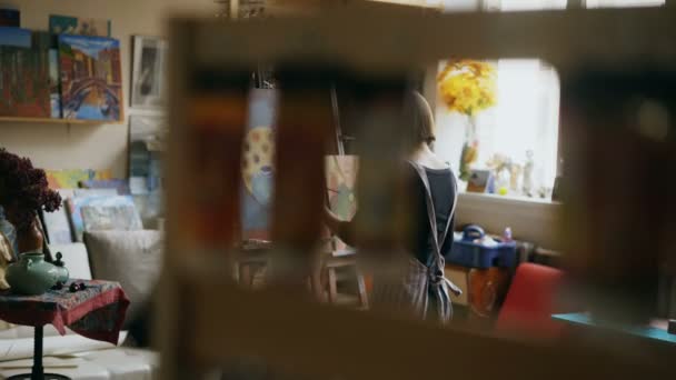 青年画家女孩的后方看法在围裙画静物画在帆布在艺术类 — 图库视频影像