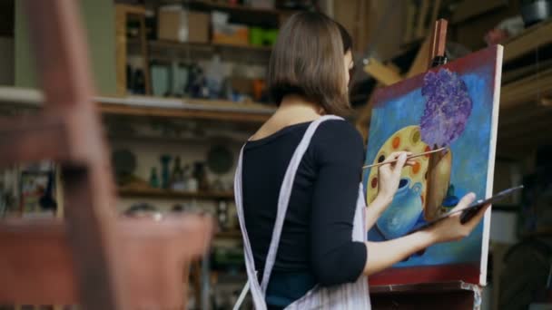 Талантливая молодая женщина-художник рисует картину на холсте в художественном классе — стоковое видео