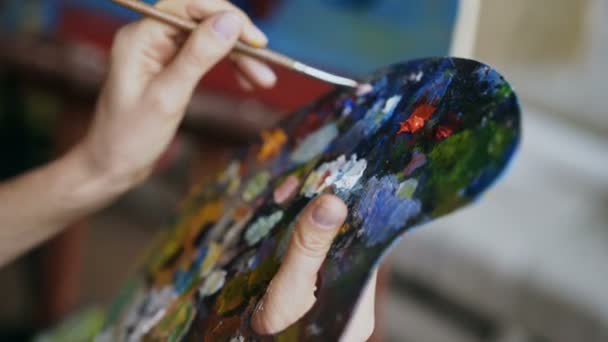Крупный план женских рук смешивают краски с кистью в палитре в художественном классе — стоковое видео