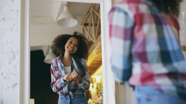 Lockig lustige afrikanisch-amerikanische Mädchen tanzen und singen mit Fön vor dem Spiegel zu Hause — Stockfoto