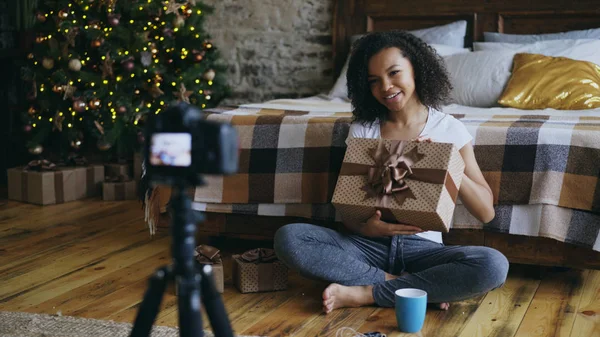 Fiatal vidám vegyes verseny lány felvétel videó blog csomagolás karácsonyi ajándék doboz otthon — Stock Fotó