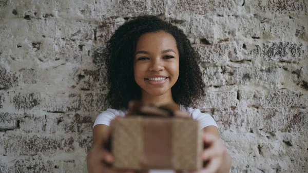 Πορτρέτο της Αφρικής ευτυχισμένη κοπέλα παρούσα συσκευασία δώρου και χαμογελά στη φωτογραφική μηχανή — Φωτογραφία Αρχείου