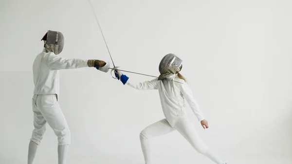 Two fencers having break after training attack exercises in fencing in studio indoors — Stock Photo, Image