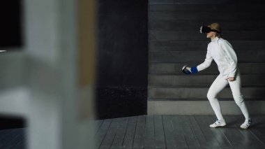 Konsantre fencer kadın pratik VR kulaklık kullanarak ve simülatör rekabet oyun kapalı eğitim egzersizleri eskrim
