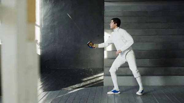 Young concentrated fencer man practice fencing exercises and training for competition in studio indoors — Stock Photo, Image