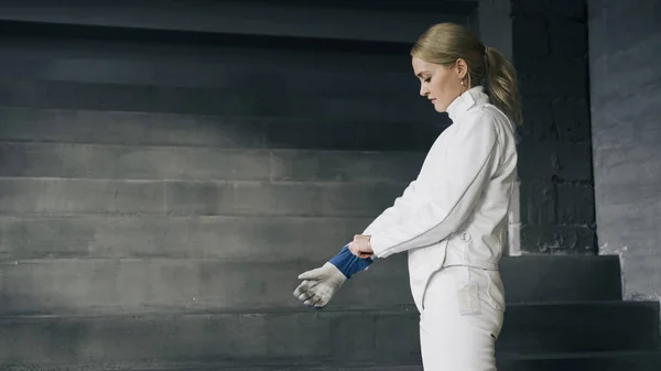 Esgrima mujer poniéndose ropa protectora y casco prepararse para la competencia de esgrima en interiores — Foto de Stock