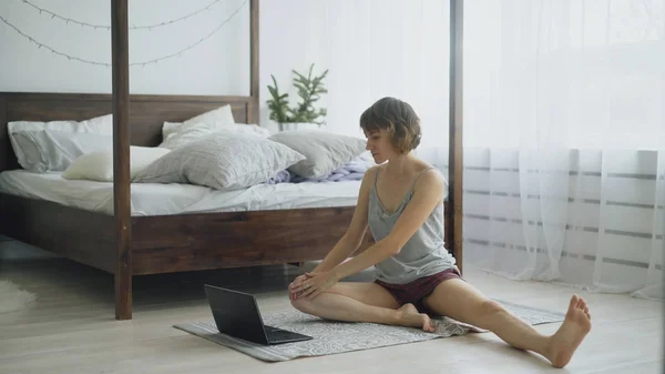 Jonge aantrekkelijke vrouw je yoga oefening doet en tutorial les op laptopcomputer thuis — Stockfoto