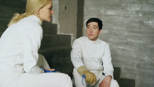Two fencers man and woman sharing experience during break of fencing match indoors — Stock Video
