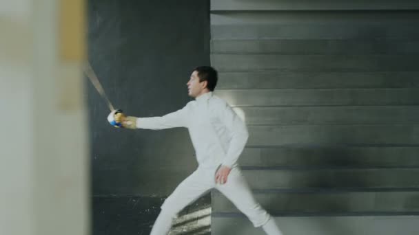 Young concentrated fencer man practice fencing exercises and training for competition in studio indoors — Stock Video