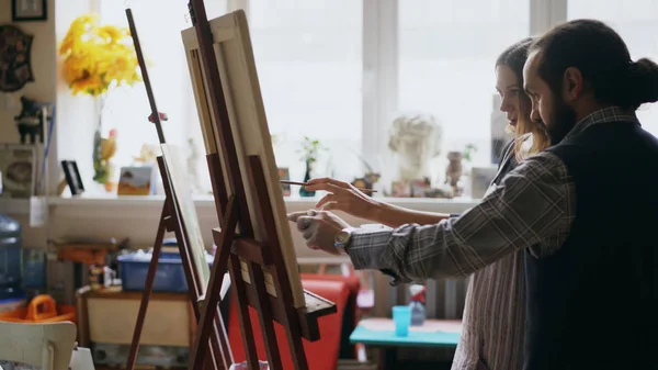 Skilled artist man teaching young girl to drawing paintings and explaining the basics in art studio — Stock Photo, Image