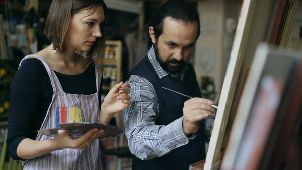 Wykwalifikowany artysta mężczyzna nauczanie młoda dziewczyna rysować obrazy i wyjaśniający podstawy w studio sztuki — Zdjęcie stockowe
